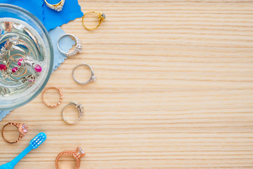 Wall Mural - cleaning jewelry diamond ring with glass of hot water and dishwashing liquid on wood table background