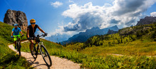Cycling Woman And Man Riding On Bikes In Dolomites Mountains Landscape. Couple Cycling MTB Enduro Trail Track. Outdoor Sport Activity.