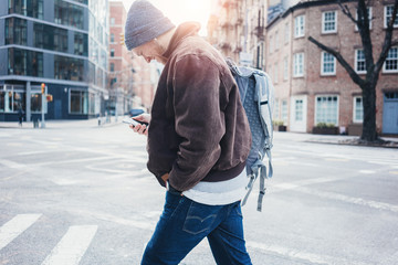 Wall Mural - Smiling man with mobile phone crossing street in the city