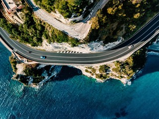 Aerial view of road going along the mountain and ocean or sea.