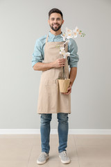 Wall Mural - Handsome male florist near light wall