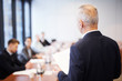 © Seventyfour - Back view portrait of senior businessman giving speech in conference room talking to employees, copy space