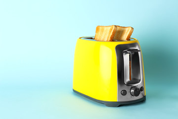 Toaster with bread slices on color background