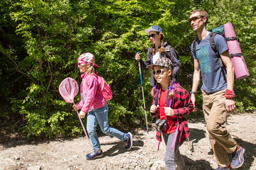 Family with two daughters travels along a beautiful path in the forest