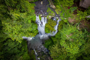 Fototapete - Aerial looking down over Sekumpul waterfall surrounded by dense rainforest and mountains shrouded in mist at sunrise, Bali, Indonesia