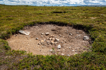 Flat highland landscape view of a large hole in the ground surrounded by green vegetation.