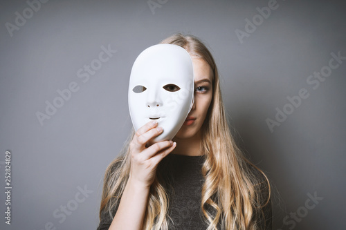 Fotomural teen girl hiding her face behind mask - identity or personality concept