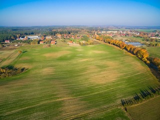 Sticker - Country road with colorful maple trees through the hilly terrain during the autumn season, Pozezdrze town in the background, Mazury, Poland