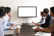 © fizkes - Business people group sitting at conference table looking at screen
