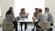 © fizkes - Middle-aged businesswoman speaking at diverse group negotiations at conference table