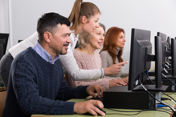 Businesswoman helping to coworkers, pointing at computer monitor