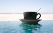 cup of coffee with spoon in cub reflection in table plastic sheet, a beach vacation scene