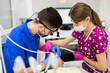 © F8  \ Suport Ukraine - Male dentist and female assistant checking up patient teeth with dental tools microscope, mirror and probe at dental clinic office. Medicine, dentistry and health care concept. Dental equipment