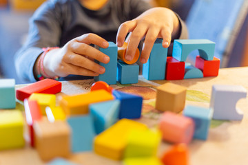 a child plays with colored wooden blocks at home.kid plays and builds buildings and towers with wooden colored blocks.