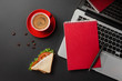 Elegant black office desktop with laptop, cup of coffee and a sandwich for lunch. Top view with copy space