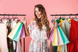 © Drobot Dean - Photo of fashionable girl standing in store near clothes rack and holding colorful shopping bags