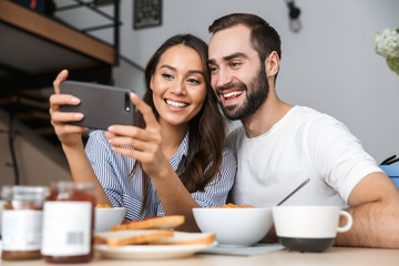 Wall Mural - Happy multiethnic couple having breakfast