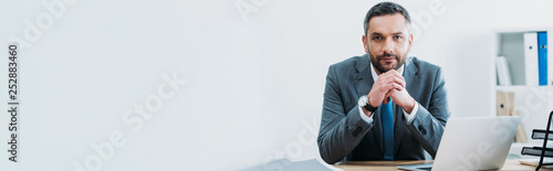 Fotomural businessman sitting at table with laptop and looking at camera in office