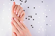 Woman's hands with a pink manicure on a white background with silver stars. Confetti.