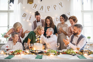 A senior man with multigeneration family celebrating birthday on indoor party.