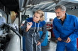 male and female mechanics using torch to examine bus
