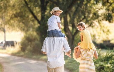 Wall Mural - A rear view of young family with small children in sunny summer nature.