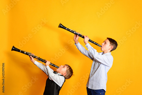 Fotografía Two children playing the clarinet, on a yellow background