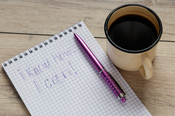 mug with coffee and a pen on a notebook with the inscription i know how! i can!