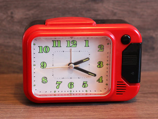 close up of a vintage red bell clock on wooden background