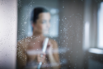 Wall Mural - Woman taking a long hot shower washing her hair in a modern design bathroom