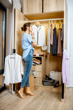 Young Woman Choosing Clothes To Wear, Standing In The Wardrobe At Home