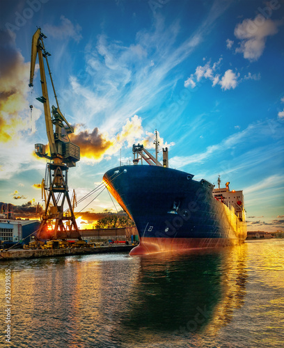 Fotografía Cargo ship in port at sunset time.