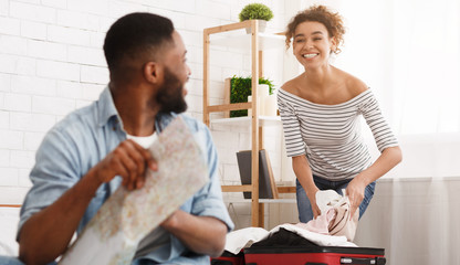 Wall Mural - Woman packing suitcase and man studying map