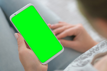 Wall Mural - Mockup image. close up. Woman's hands holding chroma key mobile phone. Green screen smartphone.