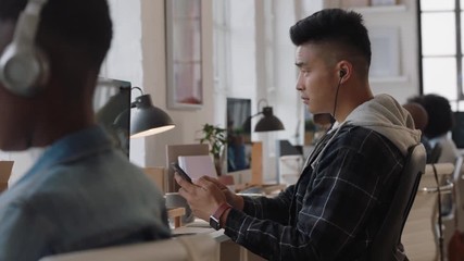 young asian man software developer using computer designing mobile application reading notes brainstorming design solution in modern office workplace