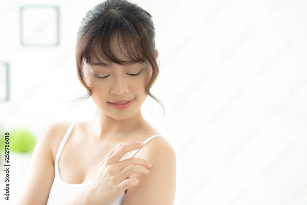 Portrait of beautiful young asian woman makeup of cosmetic, girl hand touch shoulder and smile attractive, face of beauty perfect with wellness in the bedroom with skin care and healthcare concept. - obrazy, fototapety, plakaty 