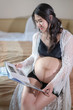 pregnant woman looking ultrasound photo album on bed