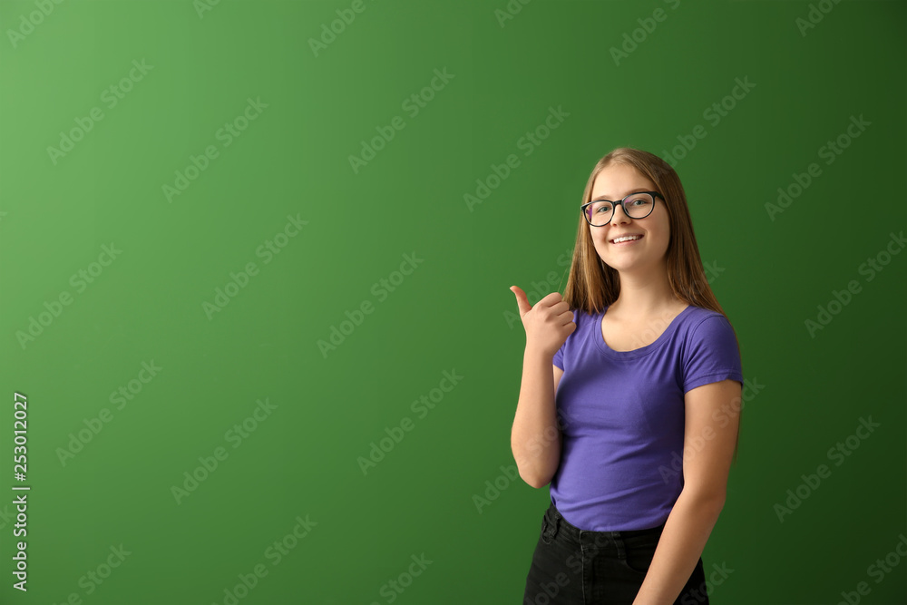 Schoolgirl showing thumb-up on color background