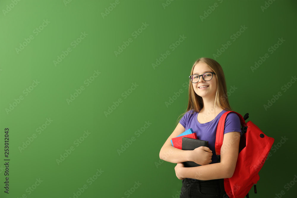 Schoolgirl with books on color background