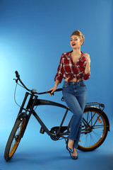 Canvas Print - Beautiful pin-up woman with bicycle on color background