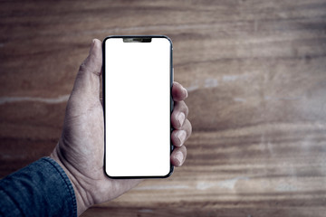 hand holding phone on wood table with blank screen.