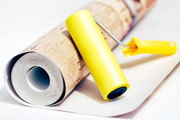 Composition tools for home repair and interior renovation indoors. Rolls of wallpaper, roller.