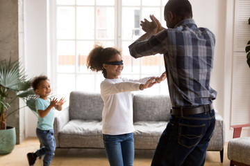 Wall Mural - Little blindfolded girl play hide and seek with family