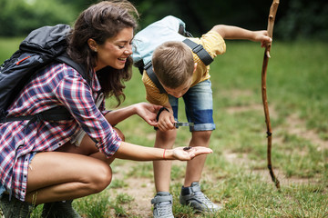 Wall Mural - mother and her little son hiking trough forest .they using magnifying glass and looking at insects.