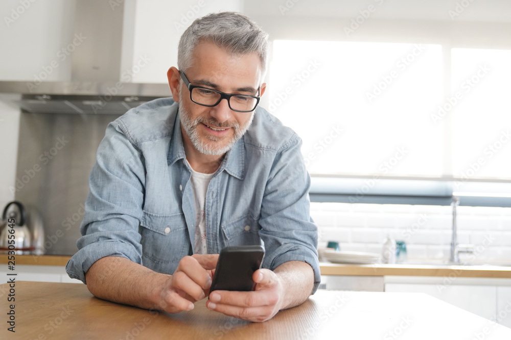 Man texting casually in kitchen at home