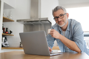 Wall Mural - Man with computer at home in modern kitchen