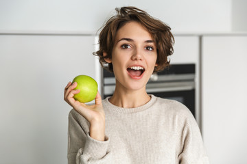 Wall Mural - Smiling young woman holding green apple