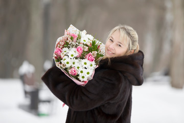 Happy woman with a bouquet of flowers on a winter background