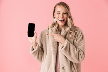 Poster - Beautiful happy young pretty woman posing isolated over pink wall background showing display of mobile phone.