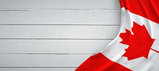canadian flag, on top of white wood. wrinkled fabric.